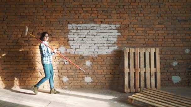 Builder dziewczyna, ciemne włosy, malować ściany z cegieł. — Wideo stockowe