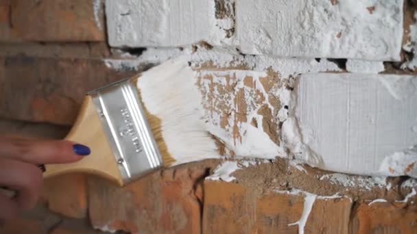 Red brick paint in white. In the hands of girls paint brush. The girl makes repairs. — Stock Video