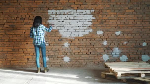 A mulher pinta um tijolo vermelho na casa na cor branca — Vídeo de Stock
