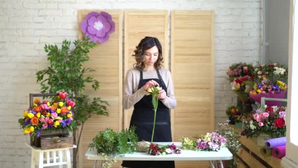 Fleuriste au travail : jolie jeune femme blonde tient bouquet moderne de différentes fleurs avec pivoine et roses en papier artisanal — Video