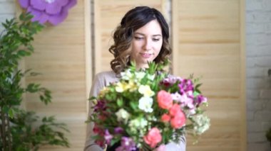 İş yerinde çiçekçi: genç ve güzel sarışın kadın tutan moda modern buket farklı peone ve gül ile Kraft kağıt