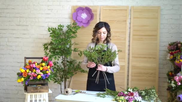 Fleuriste au travail : jolie jeune femme blonde tient bouquet moderne de différentes fleurs avec pivoine et roses en papier artisanal — Video