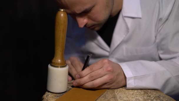 Handmatig snijden van de huid tijdens de ambachtelijke productie van lederwaren. Atelier van skinner, close-up shot weergegeven: handen van master en productieproces — Stockvideo