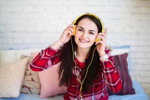 Evde kulaklıkla müzik dinleyen güzel genç bir kadın.
