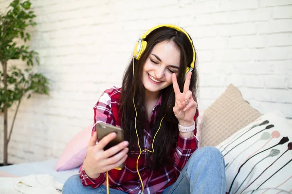 Evde kulaklıkla müzik dinleyen güzel genç bir kadın.