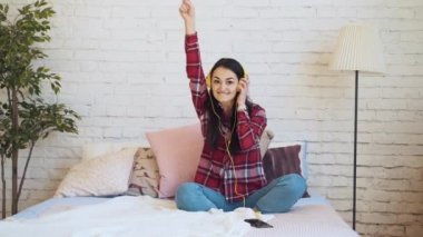 Karışık ırk kadın yatakta kulaklıklar müzik dinlemek