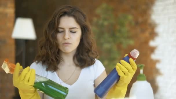 Жінка, порівнюючи засоби для миття спреїв, тримає дві пляшки і перевіряє їх — стокове відео
