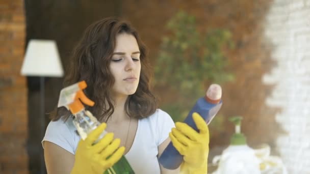 Frau vergleicht Sprühwaschmittel-Produkte, sie hält zwei Flaschen in der Hand und überprüft sie — Stockvideo