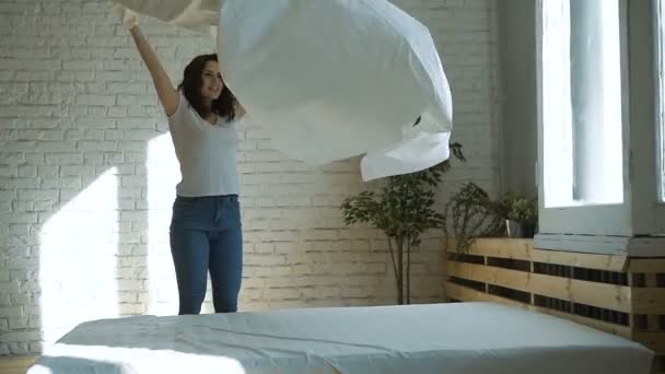 Молодая домохозяйка делает кровать необработанной — стоковое видео