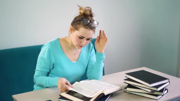 Mulher de casaco azul lendo um livro na biblioteca — Vídeo de Stock