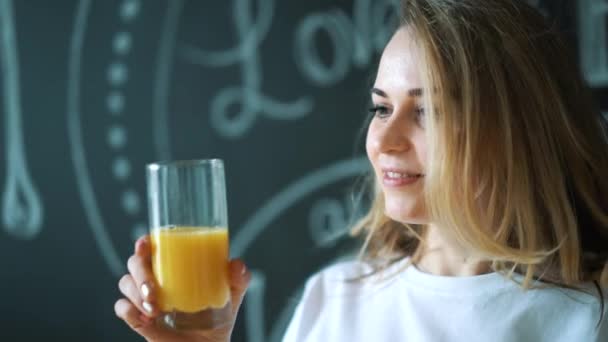 Jovem mulher bonita beber suco, menina beber laranja fresco no café da manhã — Vídeo de Stock