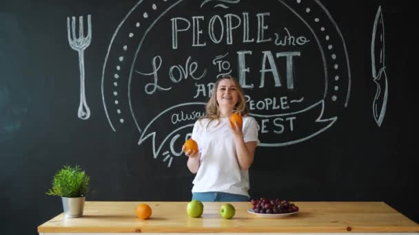 Happy girl fooling with oranges on kitchen — Stock Video