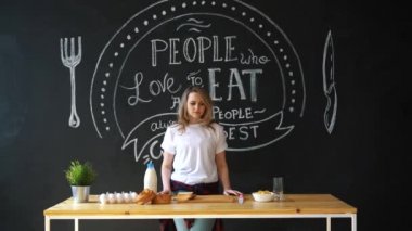 Pijama, beyaz bir t-shirt giymiş kadın çok güzel mutfakta kahvaltı evde geçirecek. Süt, topuz, pul