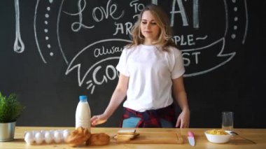 Pijama, beyaz bir t-shirt giymiş kadın çok güzel mutfakta kahvaltı evde geçirecek. Süt, topuz, pul