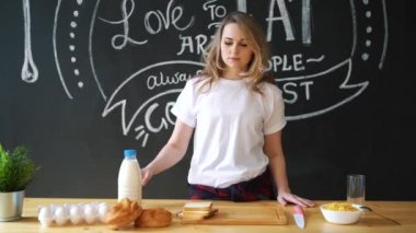 Pijama, beyaz bir t-shirt giymiş kadın çok güzel mutfakta kahvaltı evde geçirecek. Süt, topuz, pul