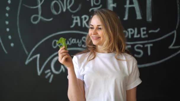Cuidado de la salud, comida y concepto de dieta - mujer sonriente mordiendo pedazo de apio o ensalada verde — Vídeo de stock