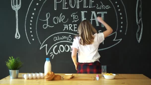 Cheerful young funny woman dancing and singing with. Cooking breakfast. — Stock Video