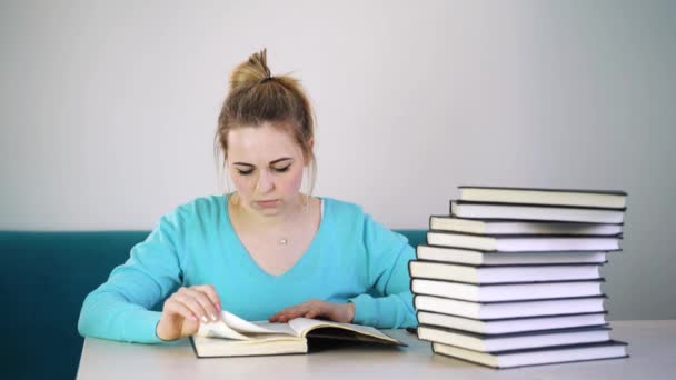 Kız öğrenci bir telefon, kitapların bir yığınına masaya iterek seçer. — Stok video