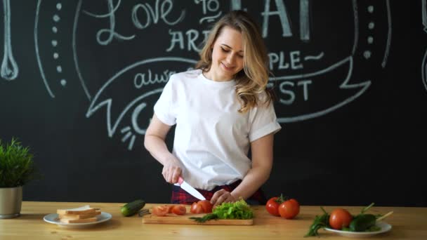 Молодая девушка веселится с помидорами на домашней кухне — стоковое видео