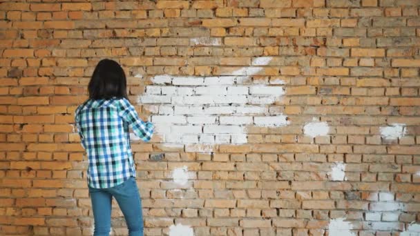 La donna dipinge un mattone rosso in casa in colore bianco — Video Stock