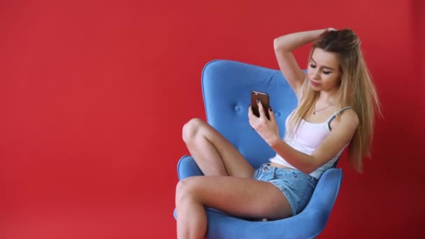 La chica en el fondo de la pared roja hablando por teléfono, vídeo, SMS, difusión . — Vídeos de Stock