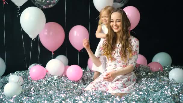 El amor de la madre y la hija abrazando y mirando a la cámara. En el festival, mamá y una niña besándose — Vídeos de Stock