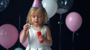 küçük kız darbe kabarcıklar arka planda konfeti ve Balon Festivali.