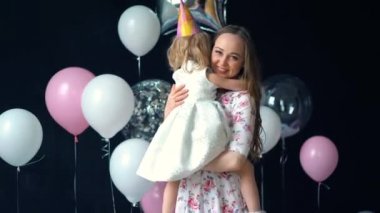 Tanrı aşkına kızı sarılma ve kameraya bakıyor. Festival, anne ve küçük bir kız öpüşme
