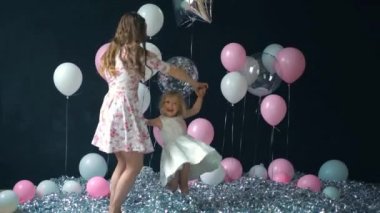 Genç anne ve kızı eğleniyor ve renkli helyum balonları ile poz portre