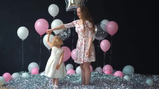 Porträtt av en ung mor och dotter ha roligt och poserar med färgglada heliumballonger — Stockvideo