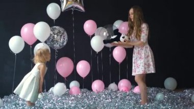 Genç anne ve kızı eğleniyor ve renkli helyum balonları ile poz portre