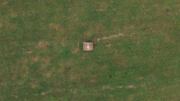 Girl lying on a haystack in a field in summer. Aerial video. — Stock Video