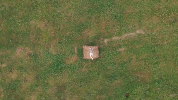 Girl lying on a haystack in a field in summer. Aerial video. — Stock Video