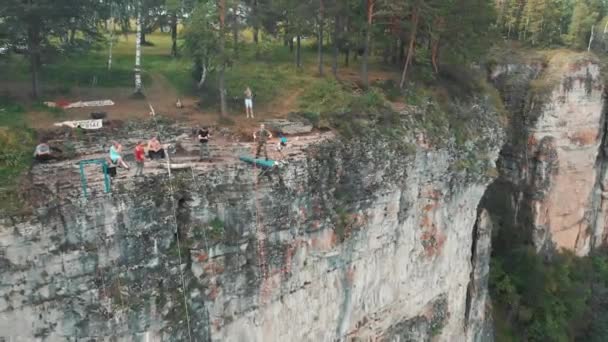 La ragazza fa il primo salto dalla scogliera su una corda. Indagine aerea — Video Stock