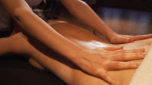 Mãos de massagista de close-up fazendo massagem giratória. A menina deitada na mesa do massagista recebe prazer da massagem . — Vídeo de Stock