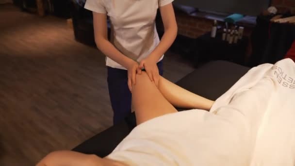 Jonge vrouw met voeten massage in de schoonheidssalon spa, close-up. Masseur kneedt de voet en het been van een jong mooi meisje. — Stockvideo