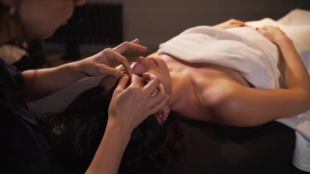 Spa kvinna ansiktsbehandling Massage. Ansiktsmassage i spa skönhetssalong. Kvinna njuta av avkopplande ansiktsmassage i kosmetologi Spa. Kroppsvård, hudvård, wellness, skönhetsbehandling. — Stockvideo