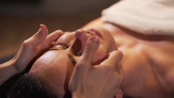 Spa kvinna ansiktsbehandling Massage. Ansiktsmassage i spa skönhetssalong. Kvinna njuta av avkopplande ansiktsmassage i kosmetologi Spa. Kroppsvård, hudvård, wellness, skönhetsbehandling. — Stockvideo