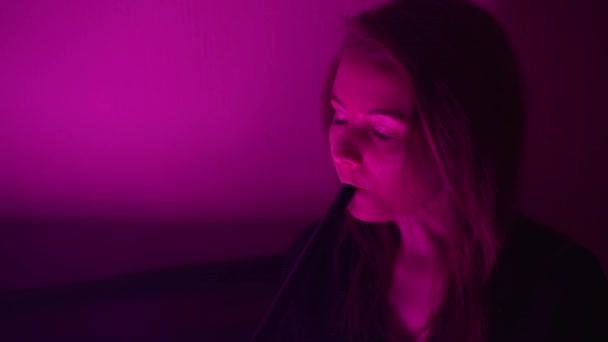 Schöne, junge, Wasserpfeife rauchende Frau. Ein attraktives Mädchen raucht aromatischen Tabak. Den Rauch im Neonlicht ausatmen — Stockvideo