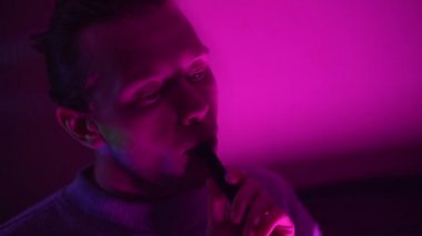 Adam sigara içmek ve neon lambaları yakmak için shisha içiyor..