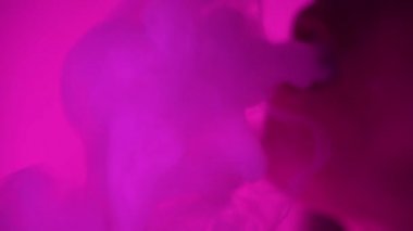 Güzel, genç, nargile tüttüren kadın. Çekici bir kız aromalı tütün içiyor. Dumanı neon ışıkta söndür.