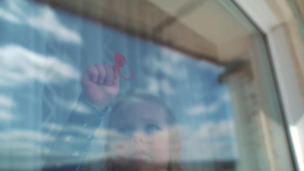 Malá holka nakreslí prst na okno srdce..