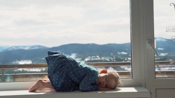 Niña triste mirando por la ventana. Niña aburrida y reflexiva, personas aisladas en cuarentena en casa, brote epidémico de virus, crisis médica . — Vídeo de stock