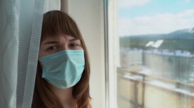 Kadınlar koruyucu mavi maskeli kadınlar, yaklaşın. Virüs enfeksiyonunun önlenmesi ve korunması için tıbbi maske takan genç bir kadın. Hastanenin penceresinde bir kadın duruyor..