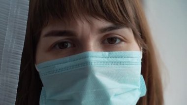 Kadınlar koruyucu mavi maskeli kadınlar, yaklaşın. Virüs enfeksiyonunun önlenmesi ve korunması için tıbbi maske takan genç bir kadın. Hastanenin penceresinde bir kadın duruyor..