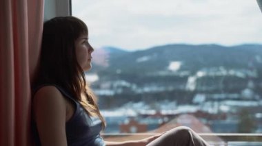 Pencere kenarında oturan genç bir kadın hayal kuruyor ve doğal ışığa bakıyor. Kendini izole etme, karantina