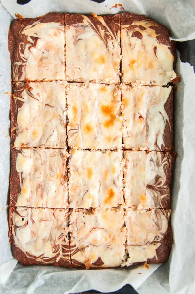 Brownie cheesecake rutor i en ugnsfast form med bakplåtspapper — Stockfoto