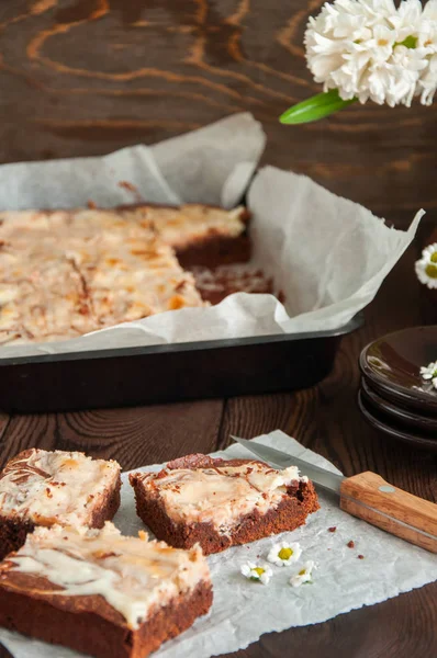 Stack av brownie cheesecake rutor på ett bakplåtspapper på en wo — Stockfoto