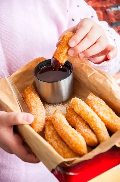 Manos de niña sosteniendo caja de metal rojo con Churros espolvoreado — Foto de Stock