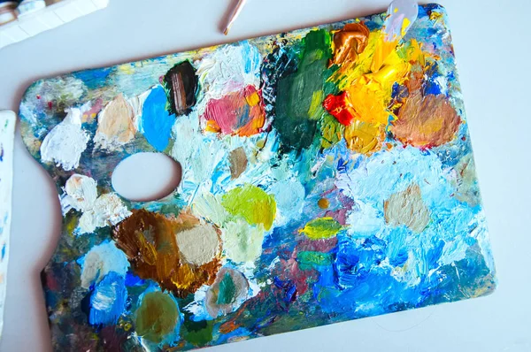 Art brushes and palette with oil paints on a table.